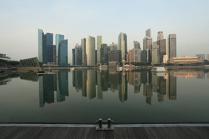 The Singapore central business district skyline reflected in the still water of Marina Bay